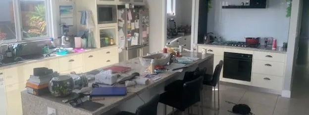 Cluttered kitchen bench and island before cleaning