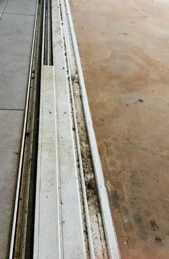 Sliding door tracks with built-up grime before cleaning
