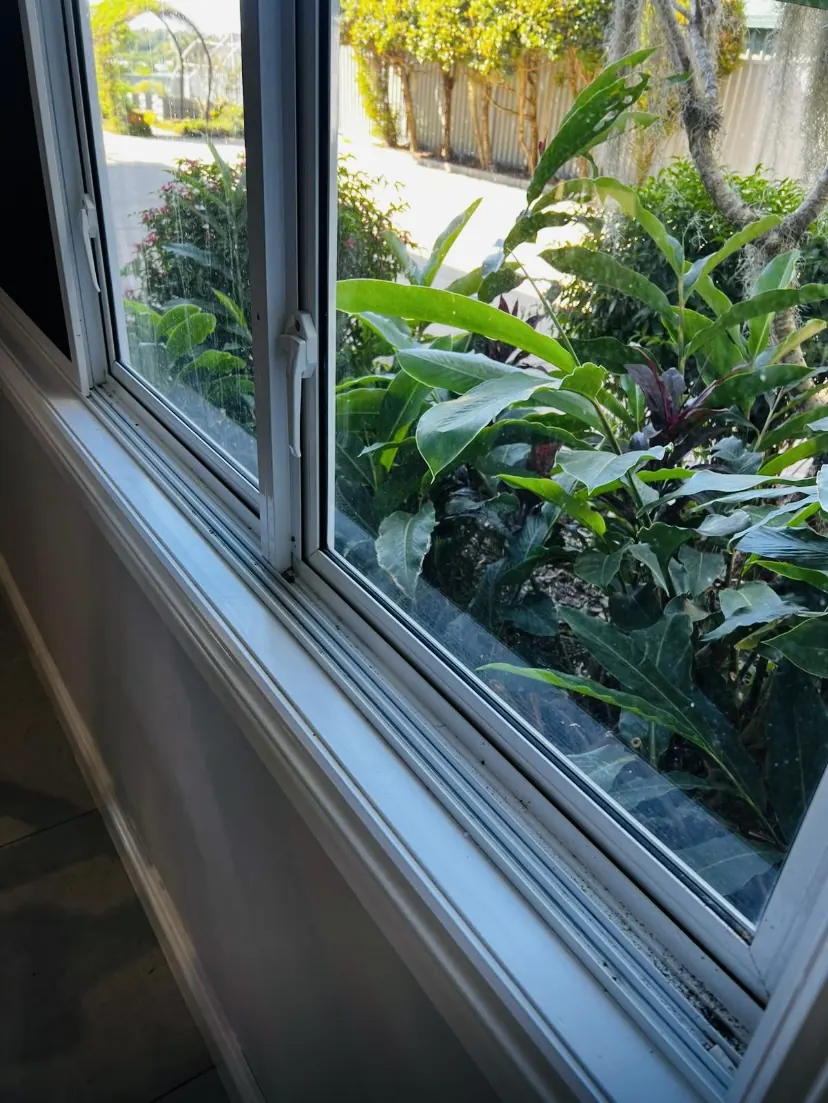 Window sill and track with dirt and grit built up along the channel before cleaning