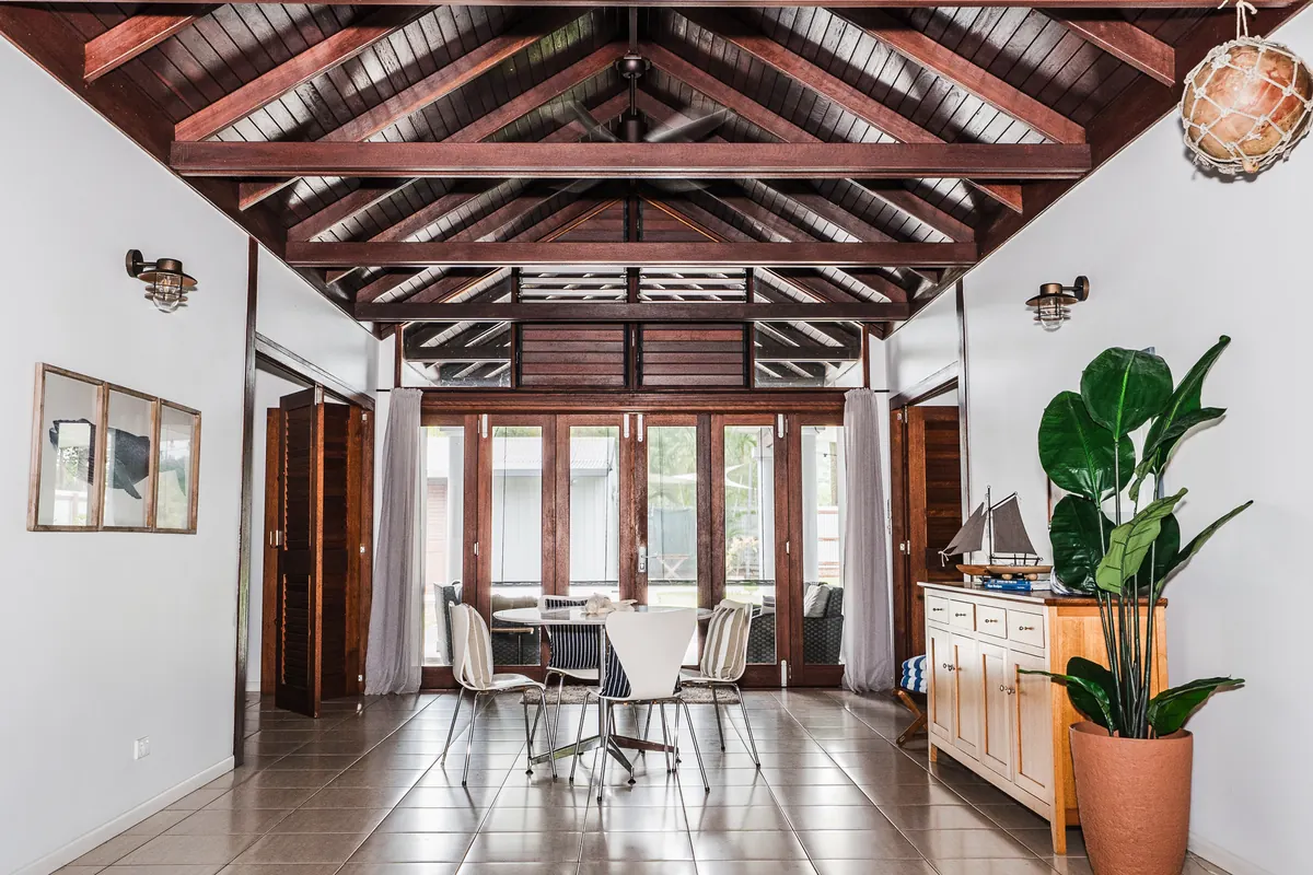 Open-plan holiday home with a soaring timber ceiling, dining setting and garden doors, cleaned and reset for the next guests
