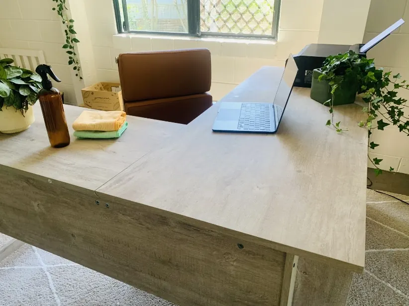 Office reception desk wiped down and reset, with a laptop, a natural cleaning spray and folded cloths