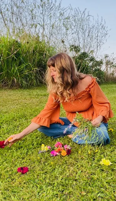 Lorraine from Citrus sitting on the grass, gathering a small posy of wildflowers to take to someone who needs a little kindness